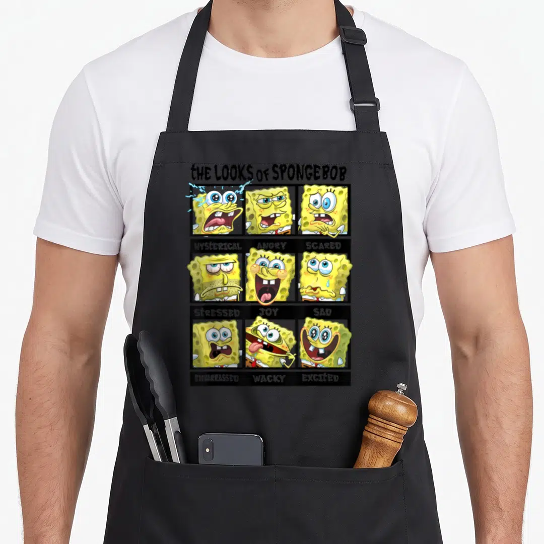 Multiple general apron - Nine SpongeBob cartoon faces in a grid labeled with emotions like angry, scared, and joyful — shown on a black cotton canvas apron against a white background