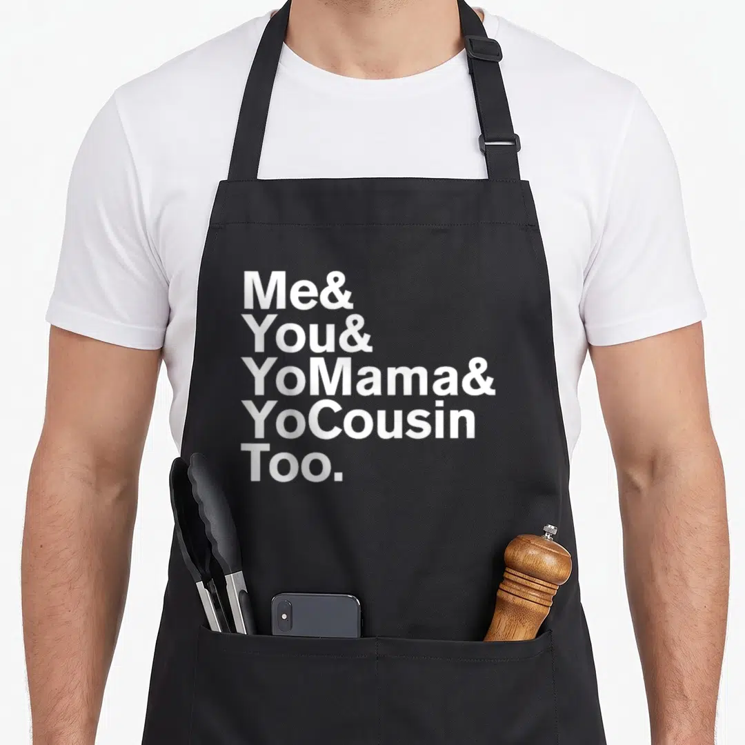 Cousin mama apron - White stacked text reading Me You Yo Mama Yo Cousin Too on black background — shown on a black cotton canvas apron against a white background
