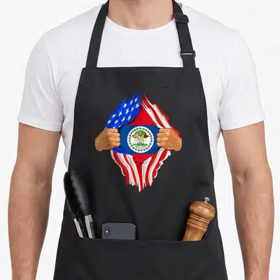 Belizean blood apron - Two hands tearing USA flag to reveal Belize flag with coat of arms in blue white red and green — shown on a black cotton canvas apron against a white background