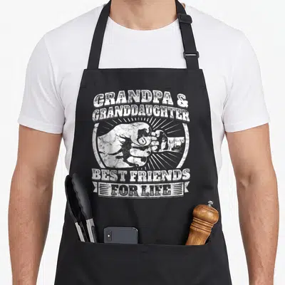 Granddaughter grandad aprons - White distressed fist bump graphic with stacked text reading GRANDPA & GRANDDAUGHTER — shown on a black cotton canvas apron against a white background
