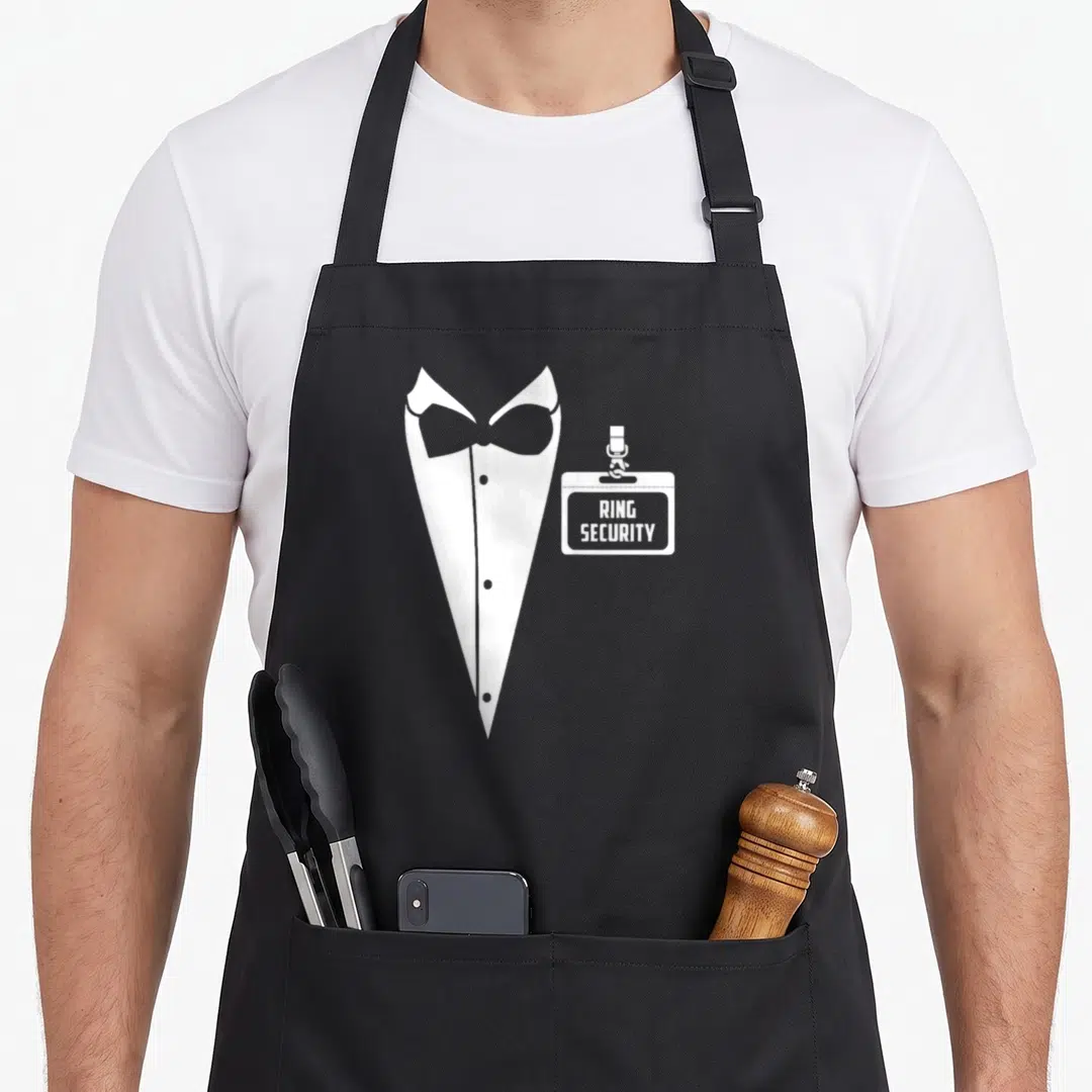 Ring tag apron - White tuxedo silhouette next to a badge printed with RING SECURITY text — shown on a black cotton canvas apron against a white background