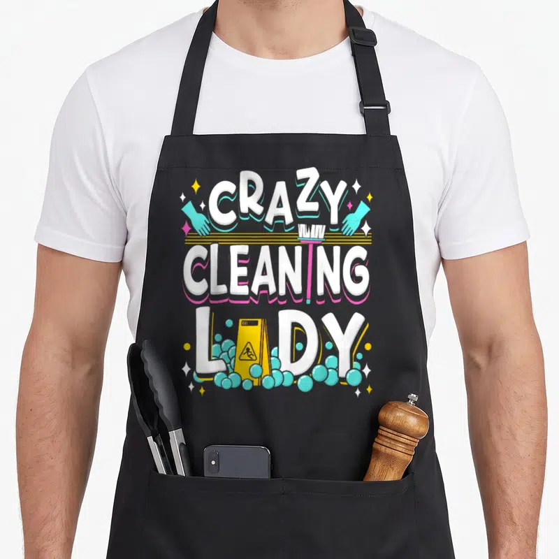 Housekeeping cleaner housekeeper apron - Stacked white text CRAZY CLEANING LADY with teal gloves, broom, and yellow — shown on a black cotton canvas apron against a white background