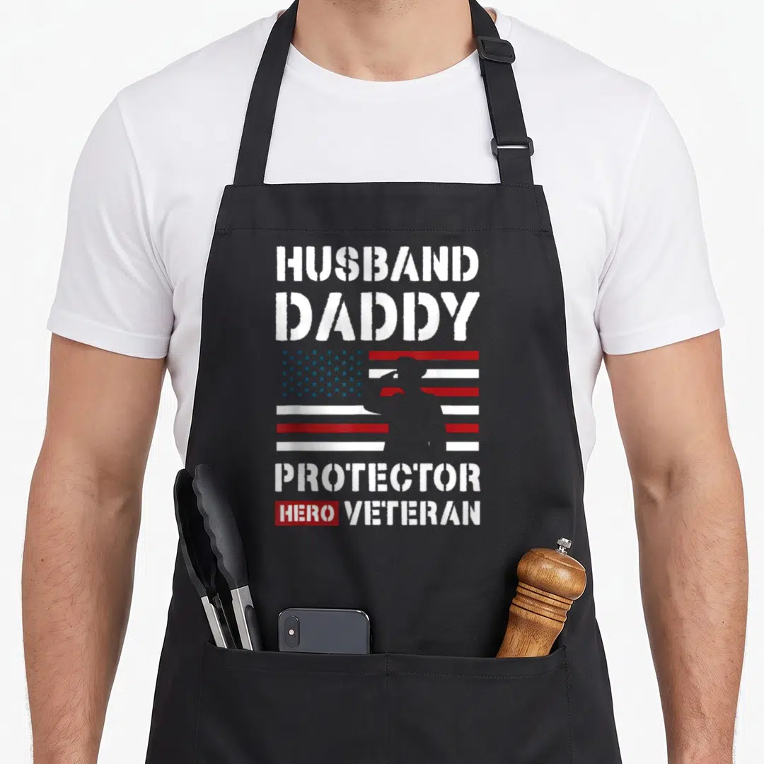 Protector best husband apron - Soldier silhouette over red blue white flag with distressed HUSBAND DADDY PROTECTOR HERO — shown on a black cotton canvas apron against a white background