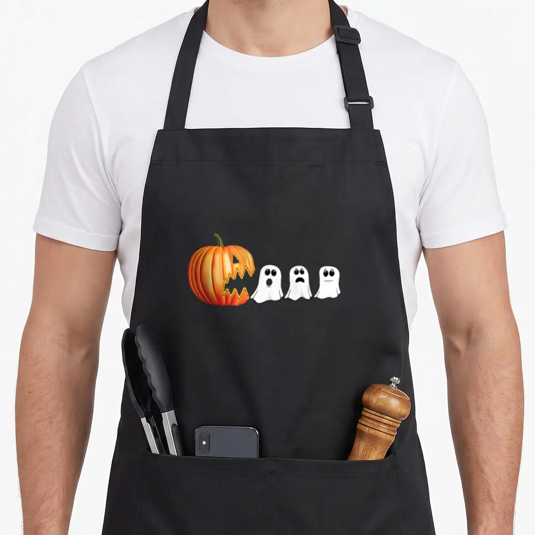 Ghost jack halloween apron - Orange pumpkin facing three white cartoon ghosts in a line — shown on a black cotton canvas apron against a white background