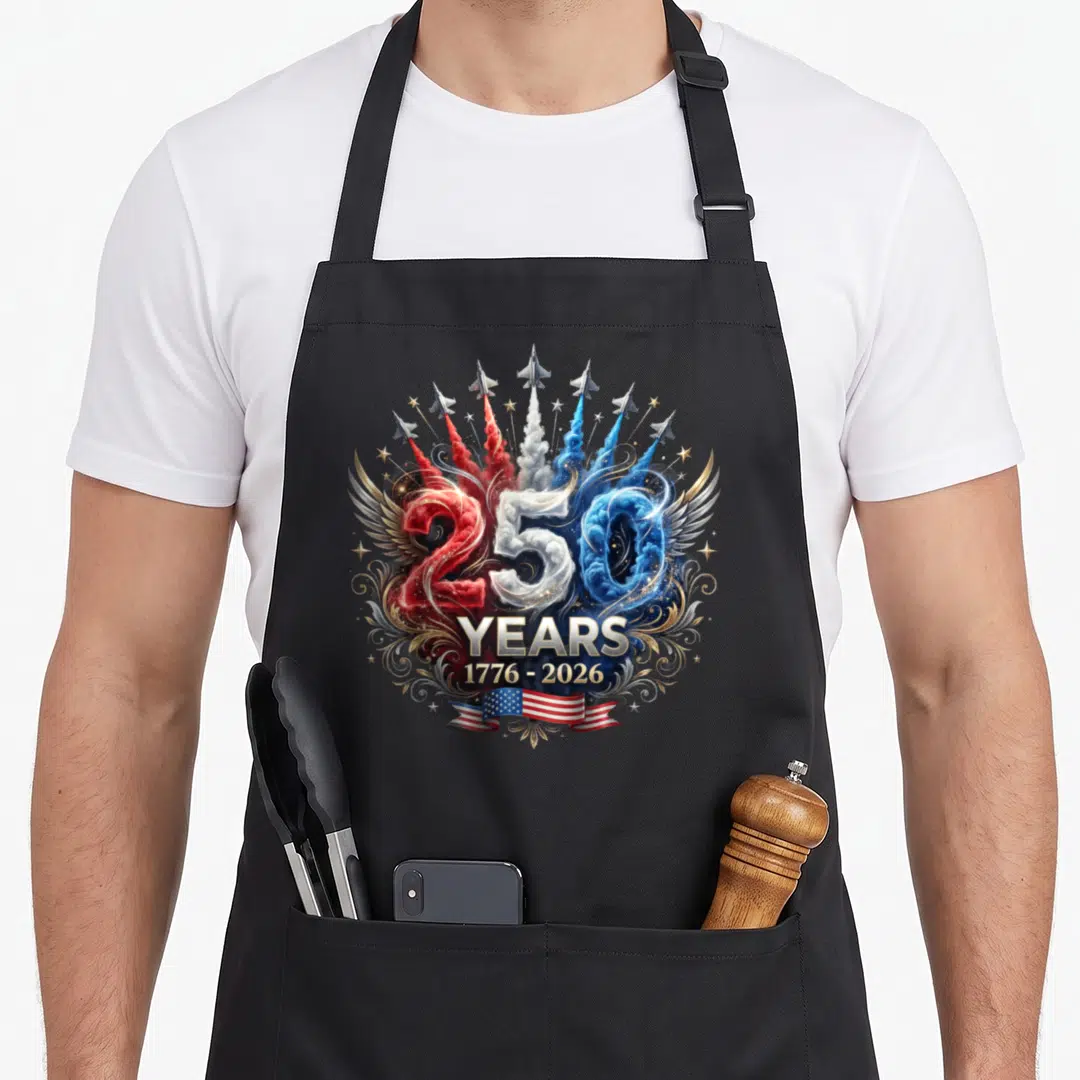 Fan patriotic apron - 250 YEARS 1776-2026 jets smoke red white blue gold flag ribbon — shown on a black cotton canvas apron against a white background