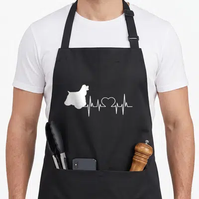 Heartbeat cocker spaniel apron - White dog silhouette connected to heartbeat line with heart shape in center — shown on a black cotton canvas apron against a white background