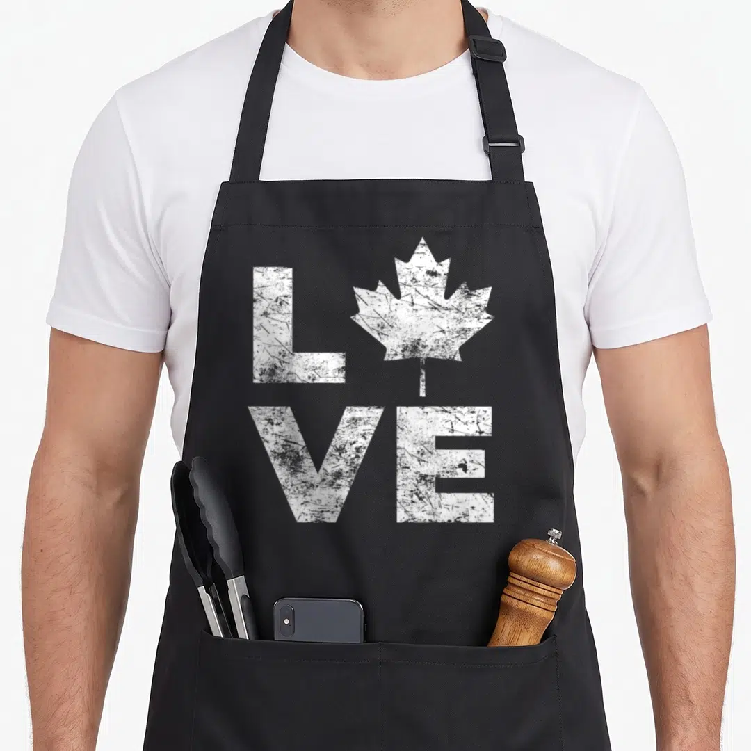 Flag maple canada aprons - White distressed LOVE text with maple leaf replacing the O letter — shown on a black cotton canvas apron against a white background
