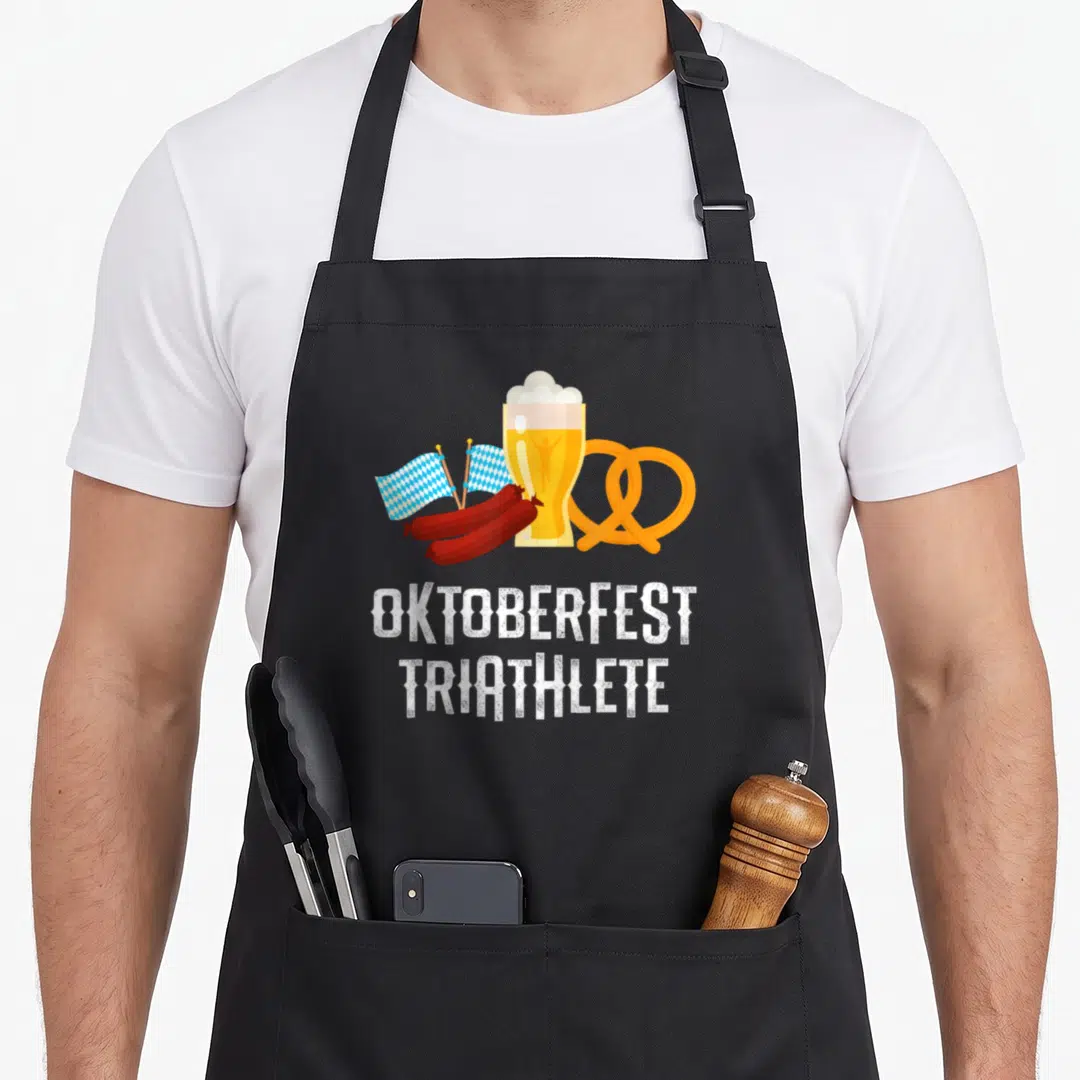 Triathlete oktoberfest apron - Beer glass with runner, pretzel, sausages, and checkered flags under stacked text — shown on a black cotton canvas apron against a white background