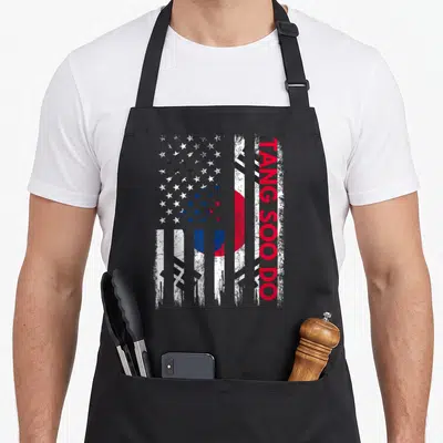 Tang korean apron - Distressed composite flag with vertical TANG SOO DO text in red white blue and black — shown on a black cotton canvas apron against a white background