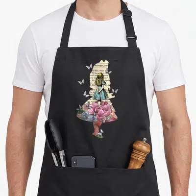Magical alice wonderland apron - Silhouette of Alice filled with vintage book text, pink flowers, and butterflies — shown on a black cotton canvas apron against a white background