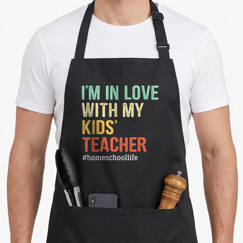 Mama cute teacher apron - Stacked I'M IN LOVE WITH MY KIDS' TEACHER text in mint beige yellow orange white — shown on a black cotton canvas apron against a white background