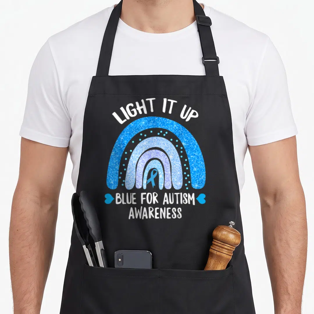 Awareness light up apron - Blue glittery rainbow with ribbon and white text reading LIGHT IT UP and BLUE FOR AUTISM — shown on a black cotton canvas apron against a white background