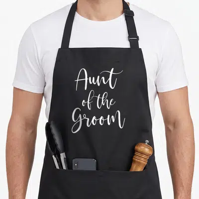 Bridal wedding day aprons - White cursive text reading Aunt of the Groom stacked on three lines — shown on a black cotton canvas apron against a white background