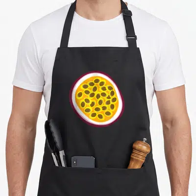 Passion fruit apron - Cartoon passion fruit cross-section showing purple rind, white pith, yellow pulp, and brown seeds — shown on a black cotton canvas apron against a white background