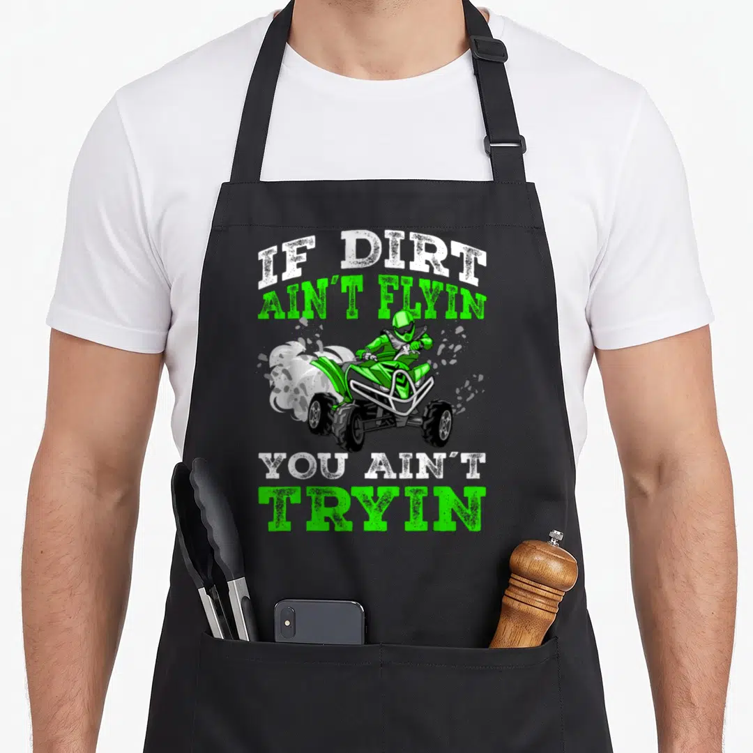 Dirt wheeler apron - ATV rider with IF DIRT AIN'T FLYIN YOU AIN'T TRYIN text in green and white distressed font — shown on a black cotton canvas apron against a white background