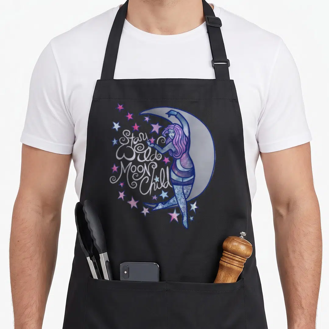 Goddess moon child apron - Stay Wild Moon Child text over woman leaning on crescent moon with pink and blue stars — shown on a black cotton canvas apron against a white background