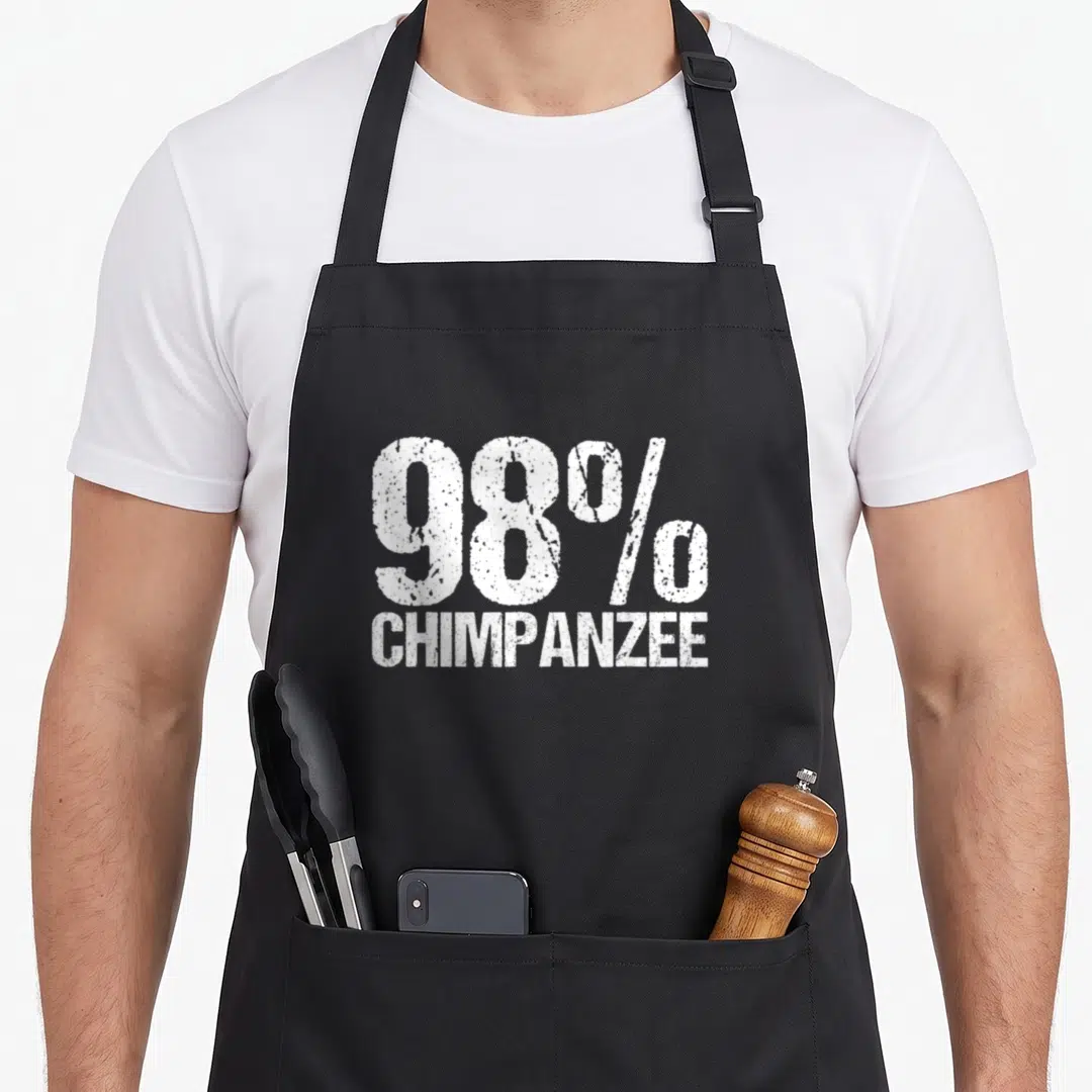 Distressed science apron - White distressed text reading 98% Chimpanzee stacked on black fabric — shown on a black cotton canvas apron against a white background