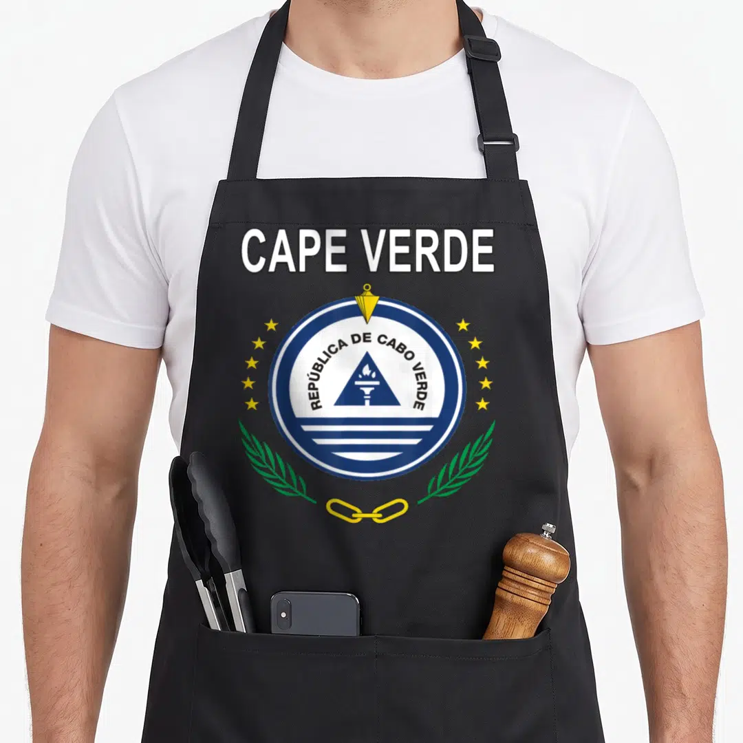 Emblem cape verde apron - CAPE VERDE text, circular coat of arms with torch, triangle, yellow stars, green leaves — shown on a black cotton canvas apron against a white background