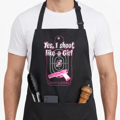 Shoot shooting apron - Pink and white shooting target with scores and handgun silhouette — shown on a black cotton canvas apron against a white background