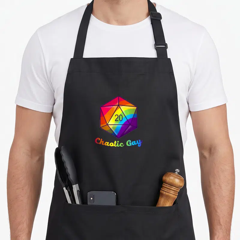 Chaotic gay pride apron - Rainbow d20 die with Chaotic Gay text in cartoon style — shown on a black cotton canvas apron against a white background