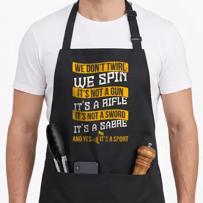Colorguard guard humor apron - Stacked text reading We Don Twirl We Spin with a small rifle graphic at the bottom — shown on a black cotton canvas apron against a white background