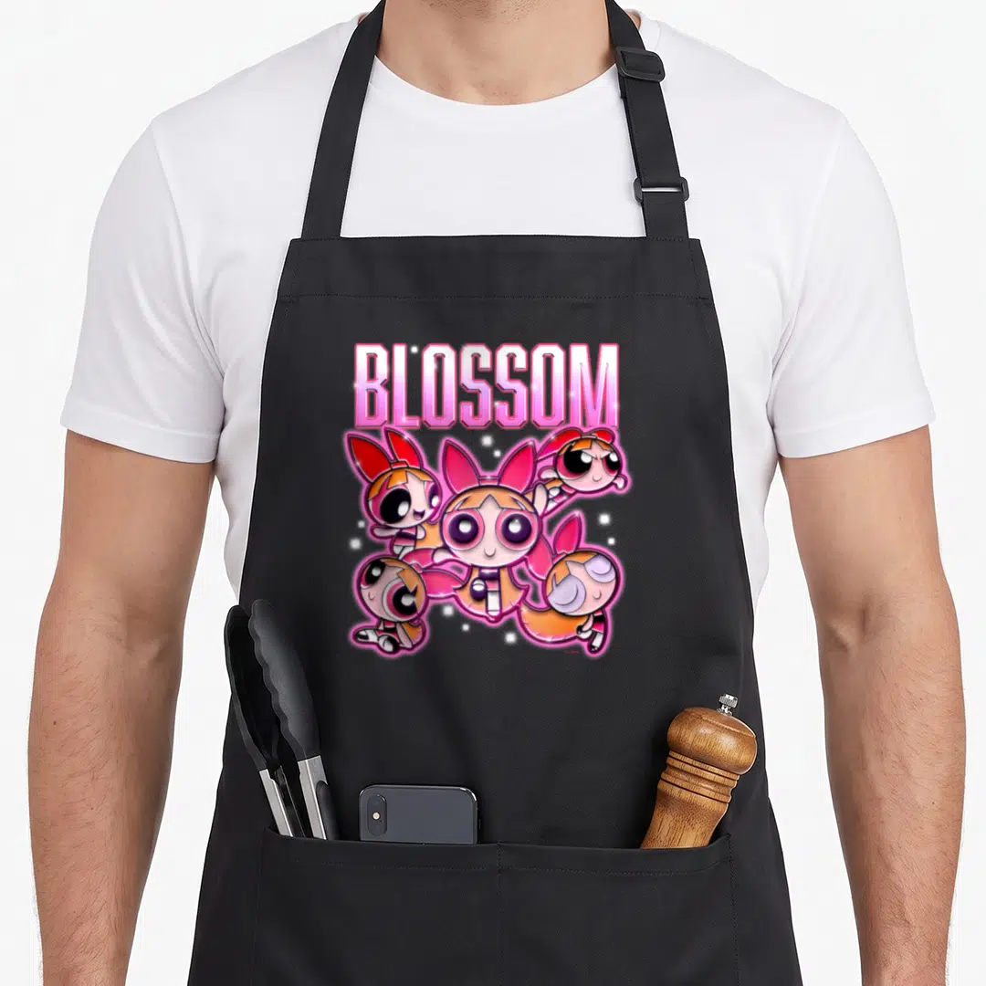 Chrome blossom apron - Pink BLOSSOM text above cartoon character with white stars and blue and green companions — shown on a black cotton canvas apron against a white background
