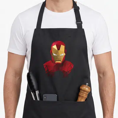 Geometric ironman apron - Low-poly geometric Iron Man helmet in red, gold, and white polygons — shown on a black cotton canvas apron against a white background
