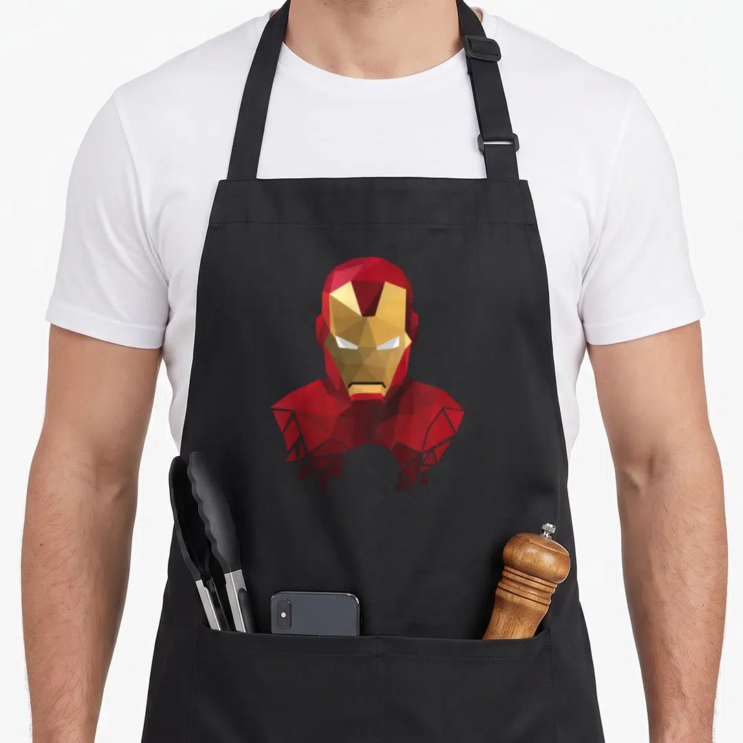 Geometric ironman apron - Low-poly geometric Iron Man helmet in red, gold, and white polygons — shown on a black cotton canvas apron against a white background