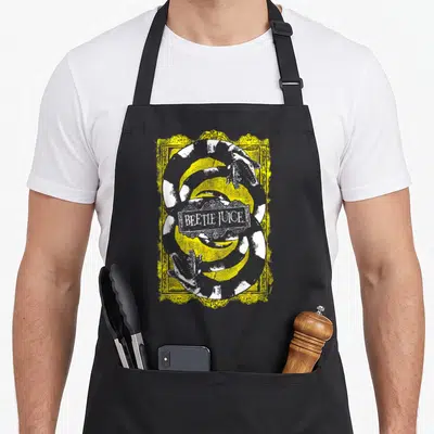 Funny worm apron - Coiled grey and white snake inside yellow frame with Beetlejuice text plaque — shown on a black cotton canvas apron against a white background