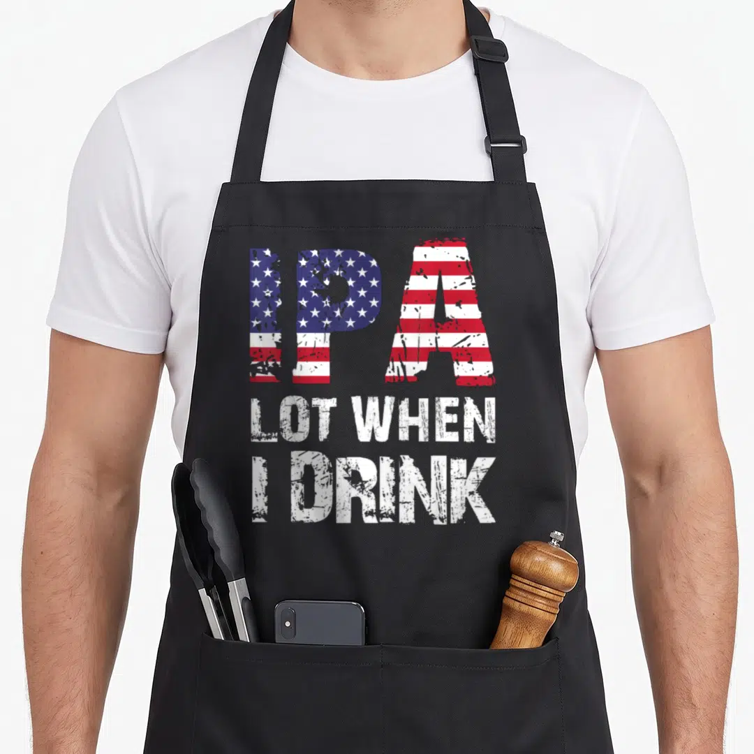 Flag beer apron - Distressed text IPA filled with US flag pattern above white LOT WHEN I DRINK lettering — shown on a black cotton canvas apron against a white background