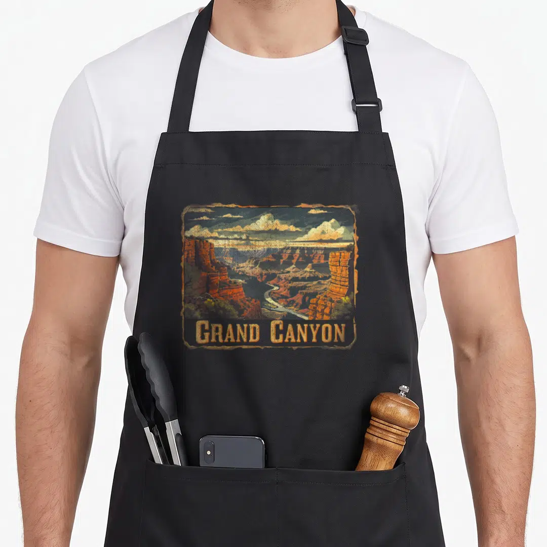Grand canyon us aprons - Retro Grand Canyon landscape with river, clouds, and orange brown blue yellow colors — shown on a black cotton canvas apron against a white background