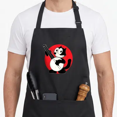Play cartoon apron - Black and white cartoon cat playing banjo on red circle — shown on a black cotton canvas apron against a white background