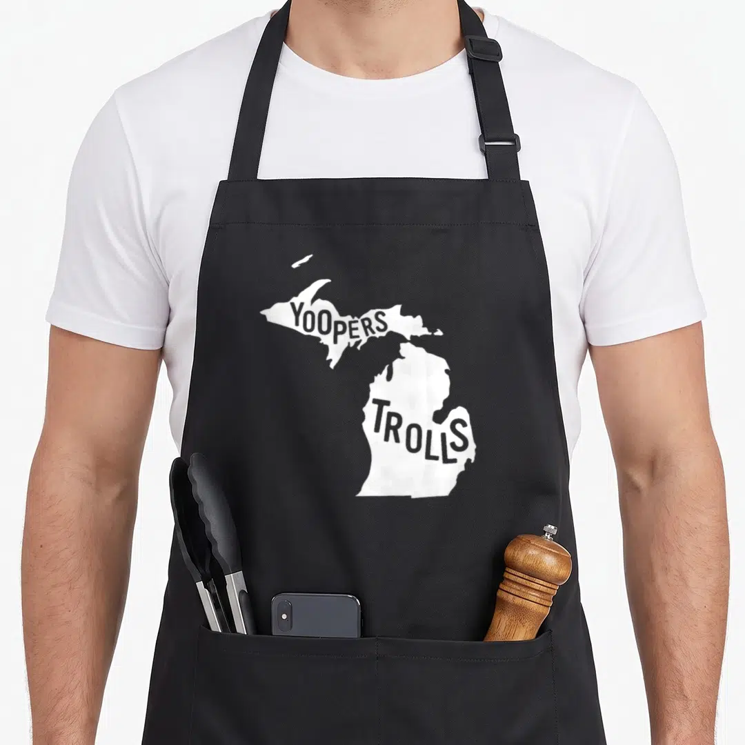 Yooper michigan boy apron - White Michigan map silhouette with YOOPERS text in Upper Peninsula and TROLLS in Lower — shown on a black cotton canvas apron against a white background