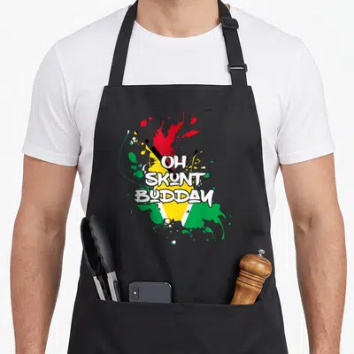 Guyana patriotic apron - OH SKUNT BUDDAY text over green yellow red white black flag paint splatters — shown on a black cotton canvas apron against a white background