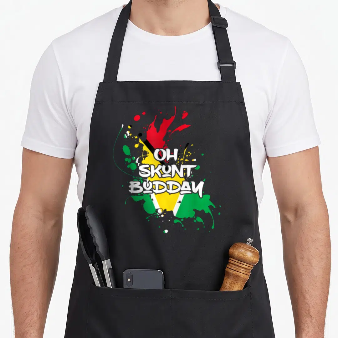 Guyana patriotic apron - OH SKUNT BUDDAY text over green yellow red white black flag paint splatters — shown on a black cotton canvas apron against a white background
