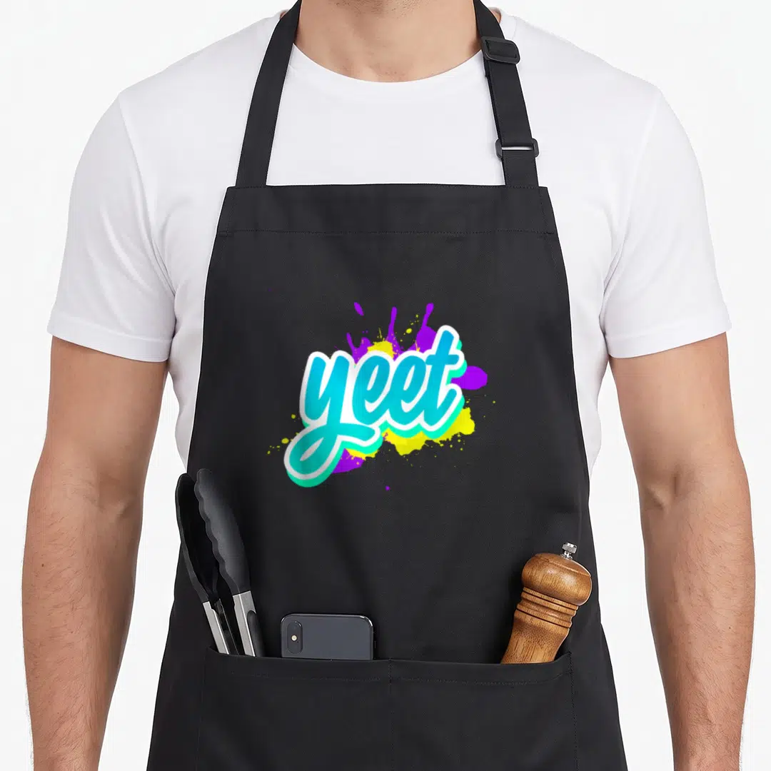 Yeet trendy apron - Cyan yeet text over purple and yellow paint splatters — shown on a black cotton canvas apron against a white background
