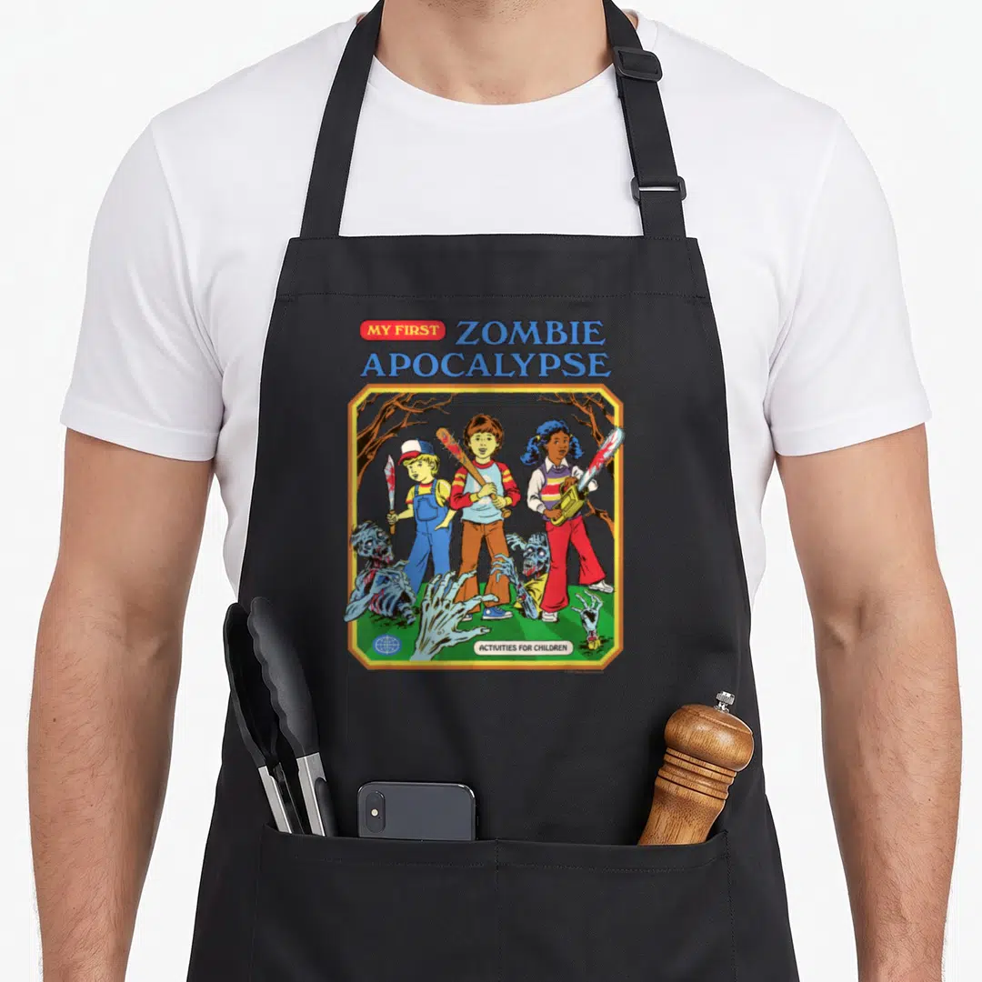 Zombie steven rhodes apron - Three cartoon children holding weapons over zombie parts with MY FIRST ZOMBIE APOCALYPSE — shown on a black cotton canvas apron against a white background