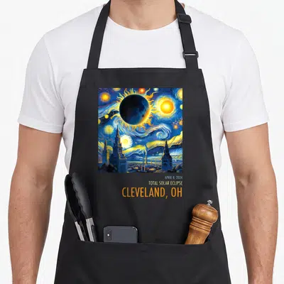 Cleveland eclipse apron - Van Gogh style solar eclipse painting over city skyline with stacked text reading April 8 — shown on a black cotton canvas apron against a white background