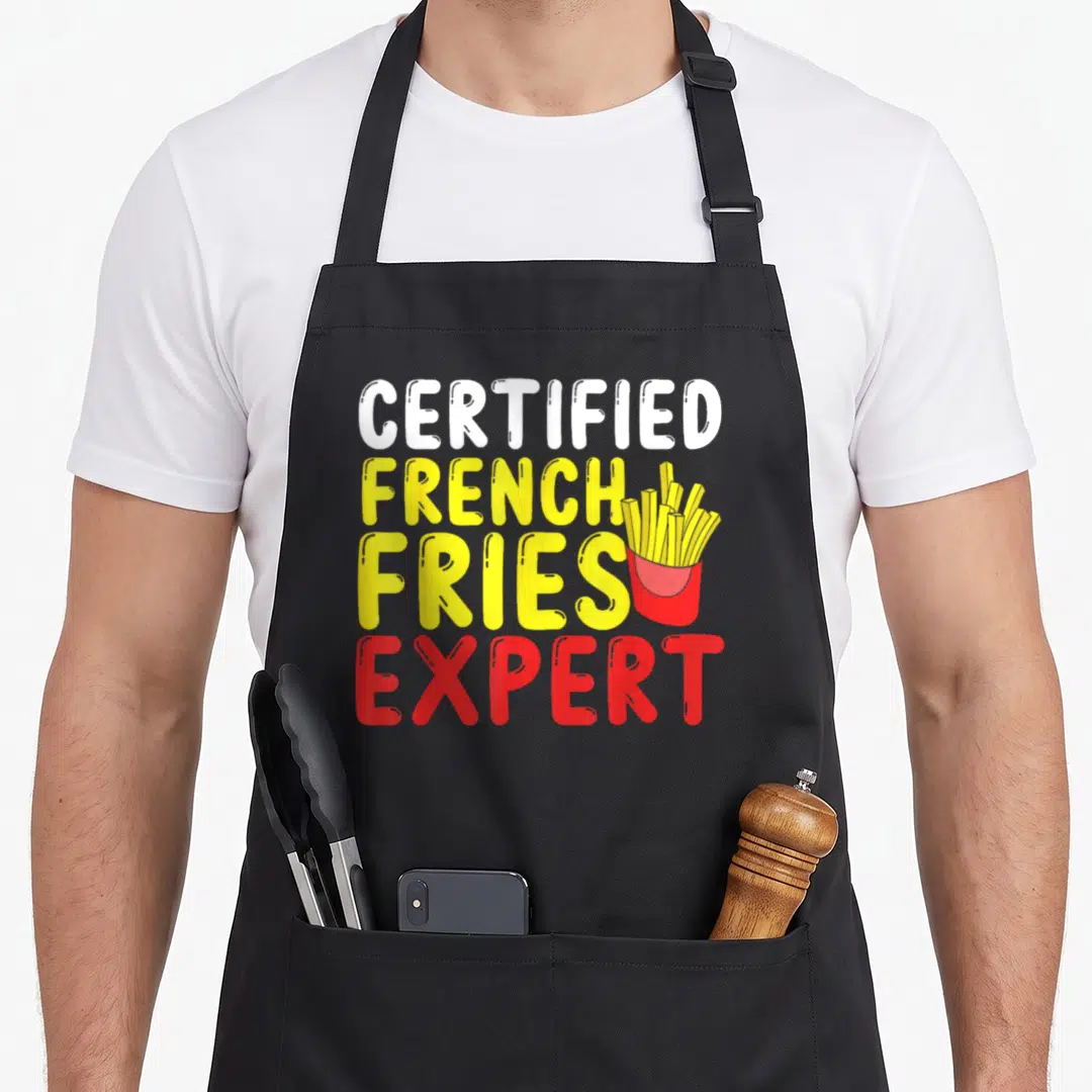 Certified french apron - Stacked CERTIFIED FRENCH FRIES EXPERT text with cartoon fries container in yellow red white — shown on a black cotton canvas apron against a white background
