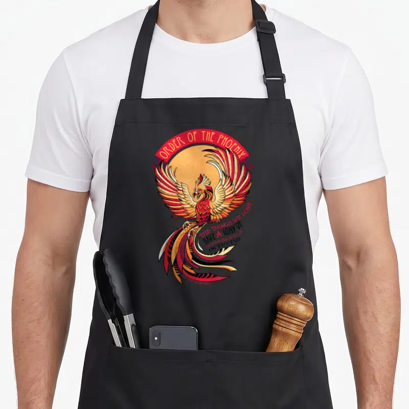 Mosaic phoenix apron - Cartoon phoenix in red and yellow with Order of the Phoenix banner and quote about lost things — shown on a black cotton canvas apron against a white background