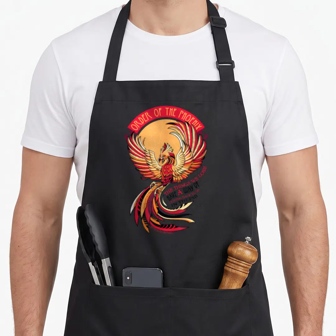 Mosaic phoenix apron - Cartoon phoenix in red and yellow with Order of the Phoenix banner and quote about lost things — shown on a black cotton canvas apron against a white background
