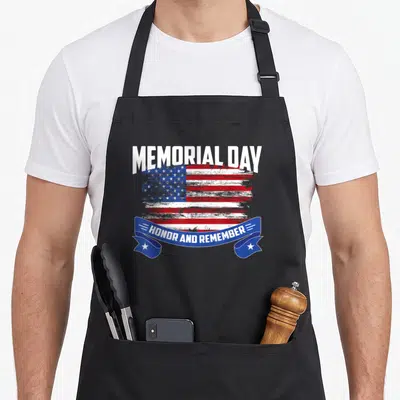 Memorial english class apron - Distressed USA flag with MEMORIAL DAY text and blue ribbon saying HONOR AND REMEMBER — shown on a black cotton canvas apron against a white background
