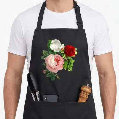 Rose floral apron - Three roses in white red and pink with green leaves and buds — shown on a black cotton canvas apron against a white background