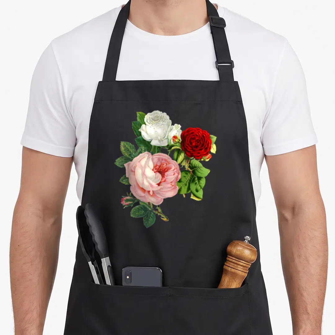 Rose floral apron - Three roses in white red and pink with green leaves and buds — shown on a black cotton canvas apron against a white background