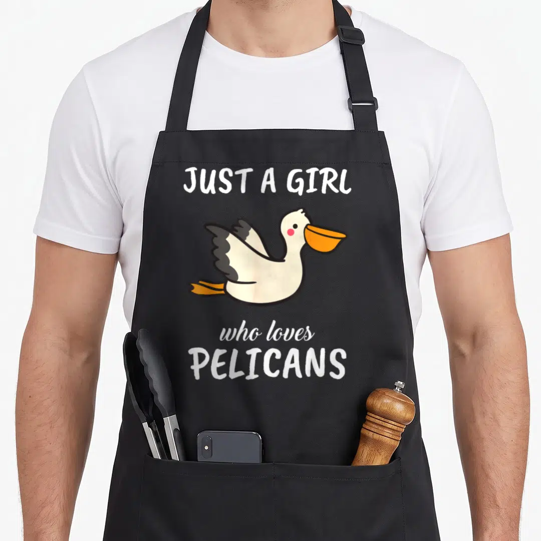 Clothe pelican apron - Cartoon pelican with orange beak framed by white text on grey background — shown on a black cotton canvas apron against a white background
