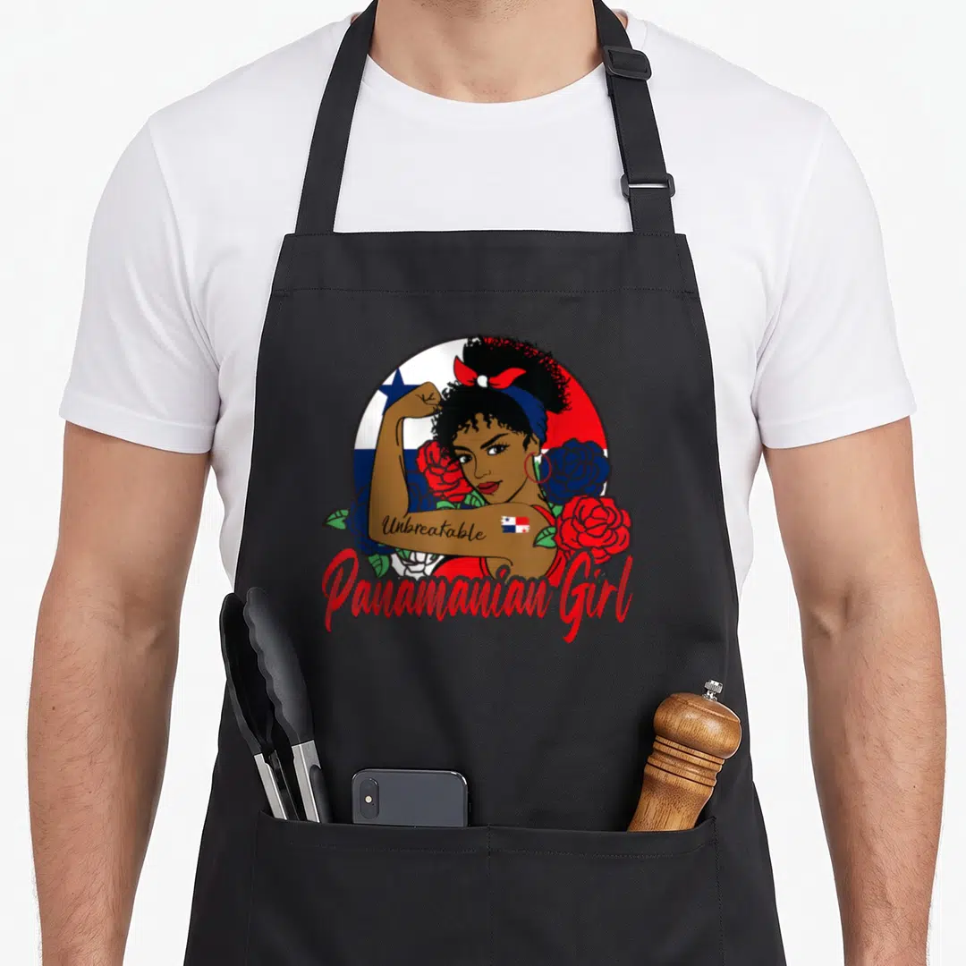 Unbreakable pride apron - Cartoon woman flexing arm with Unbreakable tattoo, Panamanian flag circle, and red and blue — shown on a black cotton canvas apron against a white background