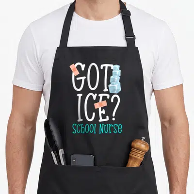 Ice nurse apron - GOT ICE text with ice cubes, bandages, and SCHOOL NURSE in cyan — shown on a black cotton canvas apron against a white background