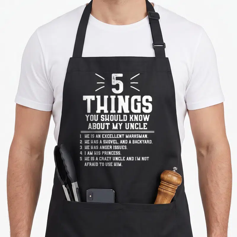 Should niece apron - White distressed text listing 5 things to know about a crazy uncle with a shovel and anger issues — shown on a black cotton canvas apron against a white background