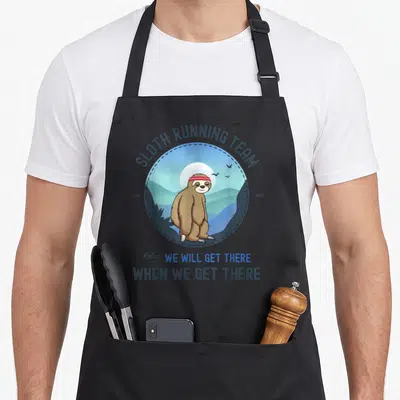 Vintage running sloth apron - Cartoon brown sloth with red headband in blue circle with text SLOTH RUNNING TEAM EST 1983 — shown on a black cotton canvas apron against a white background