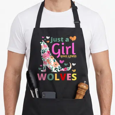Wolve floral apron - Floral wolf silhouette with hearts and text Just a Girl WHO LOVES WOLVES in pink yellow and green — shown on a black cotton canvas apron against a white background
